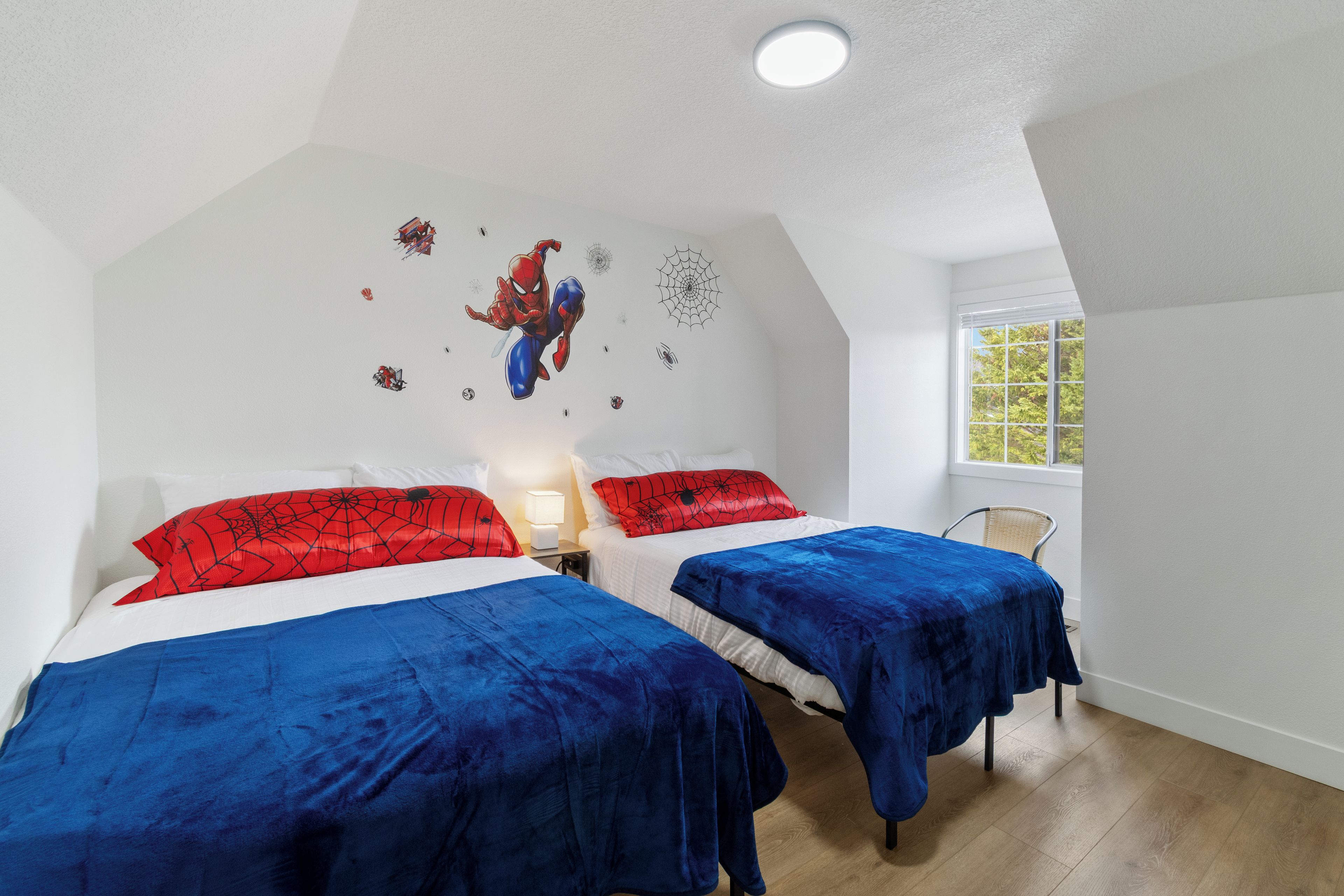 A bedroom with two beds, a window, and a ceiling light.