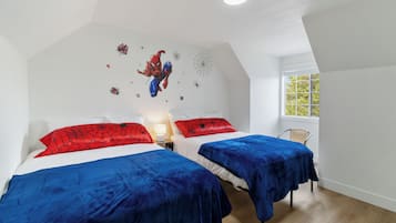 A bedroom with two beds, a window, and a ceiling light.