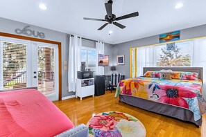 Un dormitorio con cama, escritorio, silla, ventilador de techo y ventana con persianas.