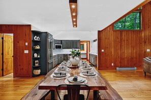 A modern kitchen with dark cabinets, a central island, and a dining area with a wooden table set for six. - 5 Primary En-Suites on First Floor, Hot Tub, Sauna (Wintergreen Resort)