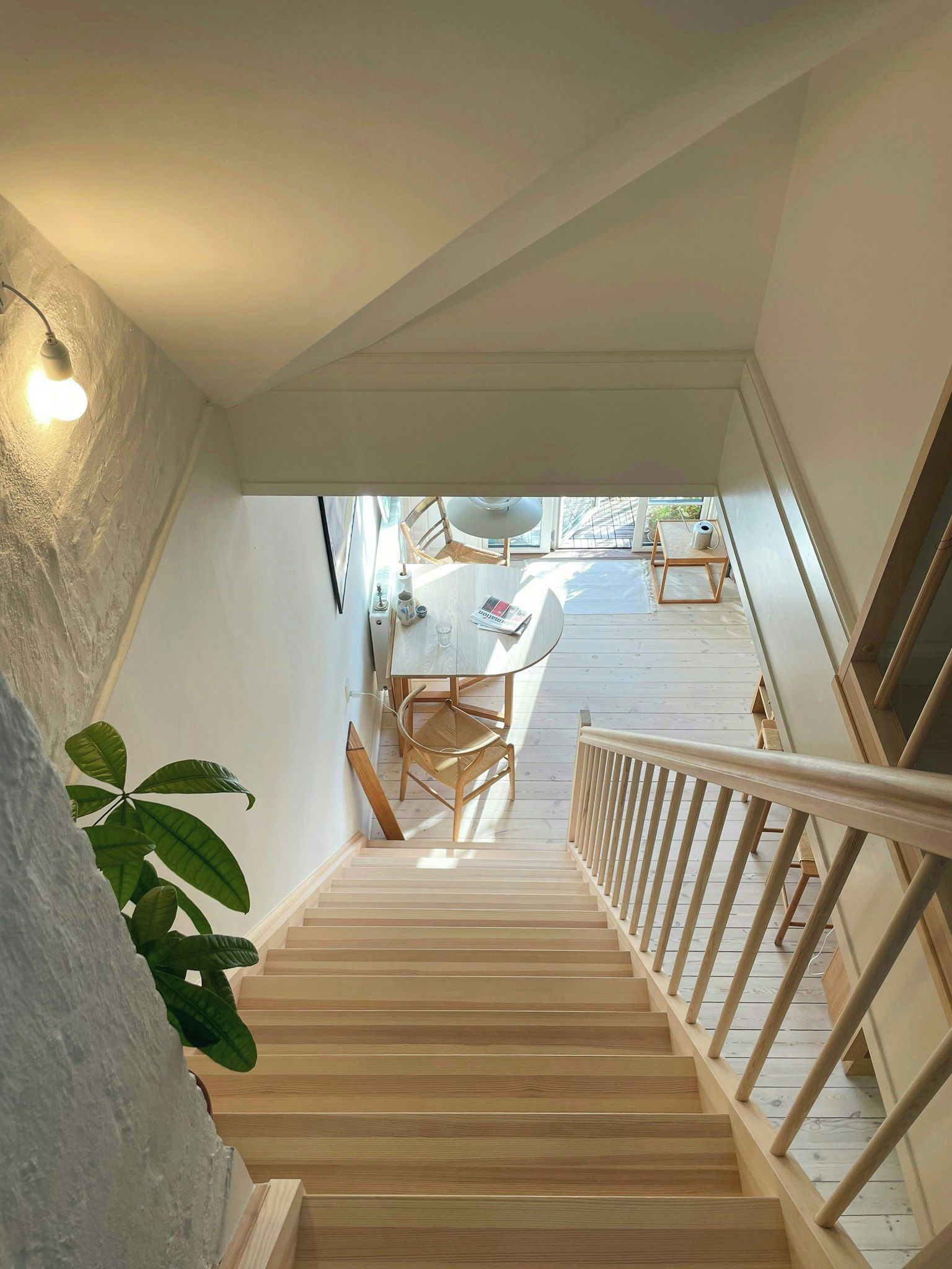 A wooden staircase leading to a dining area with a table and chairs.