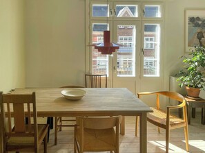 A dining area with a wooden table, chairs, a bowl, and a red pendant light. - Two-floor flat with balcony in Vesterbro (København V)