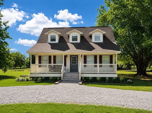 A two-story house with a front porch, a driveway, and a well-maintained lawn. - Charming Boyce Farmhouse (Boyce)