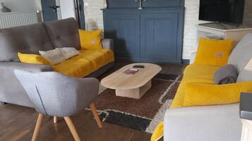Un salon avec un canapé gris, un canapé jaune, une table basse et un fauteuil gris.