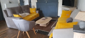 A living room with a grey sofa, a yellow sofa, a coffee table, and a grey armchair.