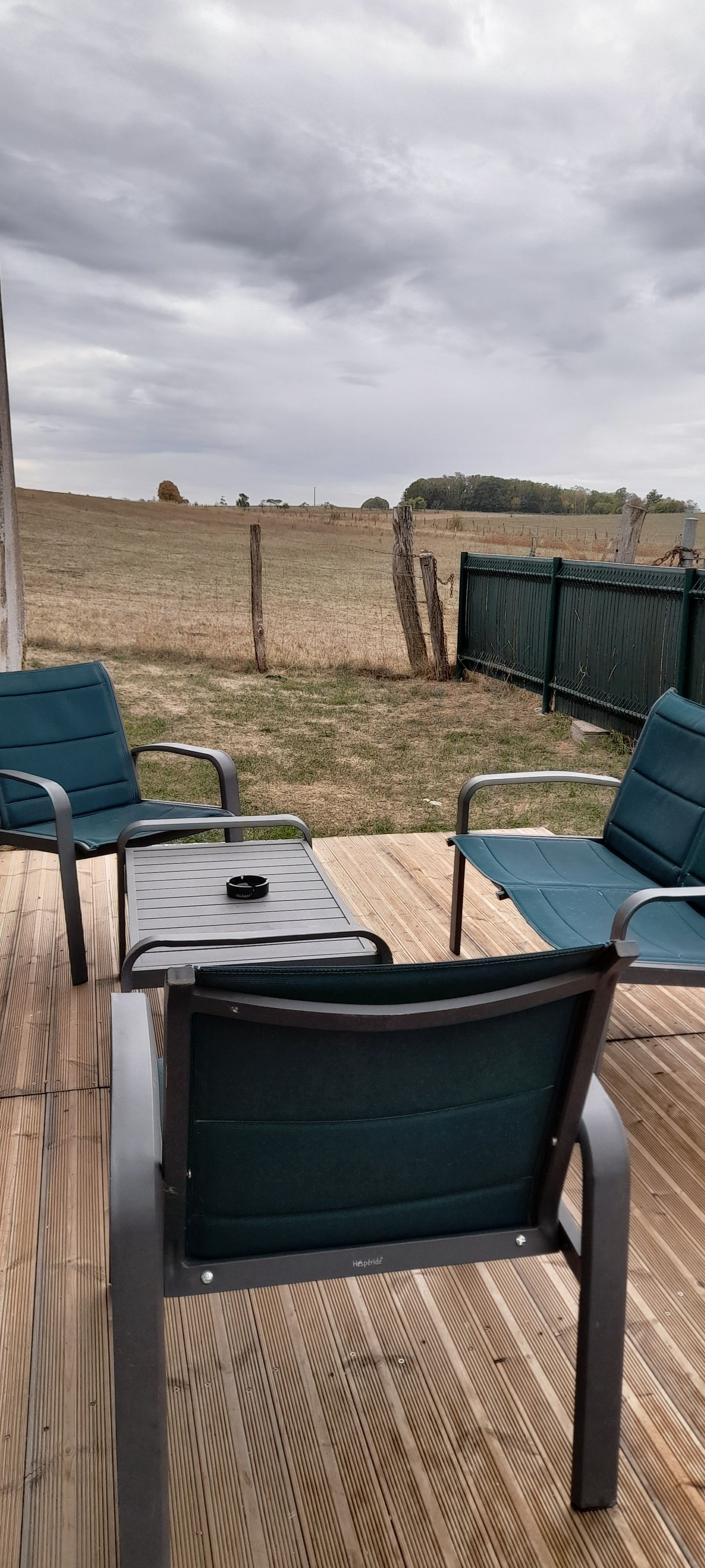 Een terras buiten met een tafel en stoelen, met uitzicht op een veld.