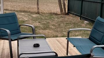 Een terras buiten met een tafel en stoelen, met uitzicht op een veld.