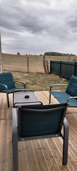 An outdoor patio with a table and chairs, overlooking a field.
