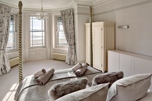 A bedroom with a four-poster bed, a large wardrobe, and a view of the sea through the windows. - Memory House (Woolacombe)