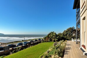 A coastal view with a parking area, a grassy lawn, and a building with a balcony. - Memory House (Woolacombe)