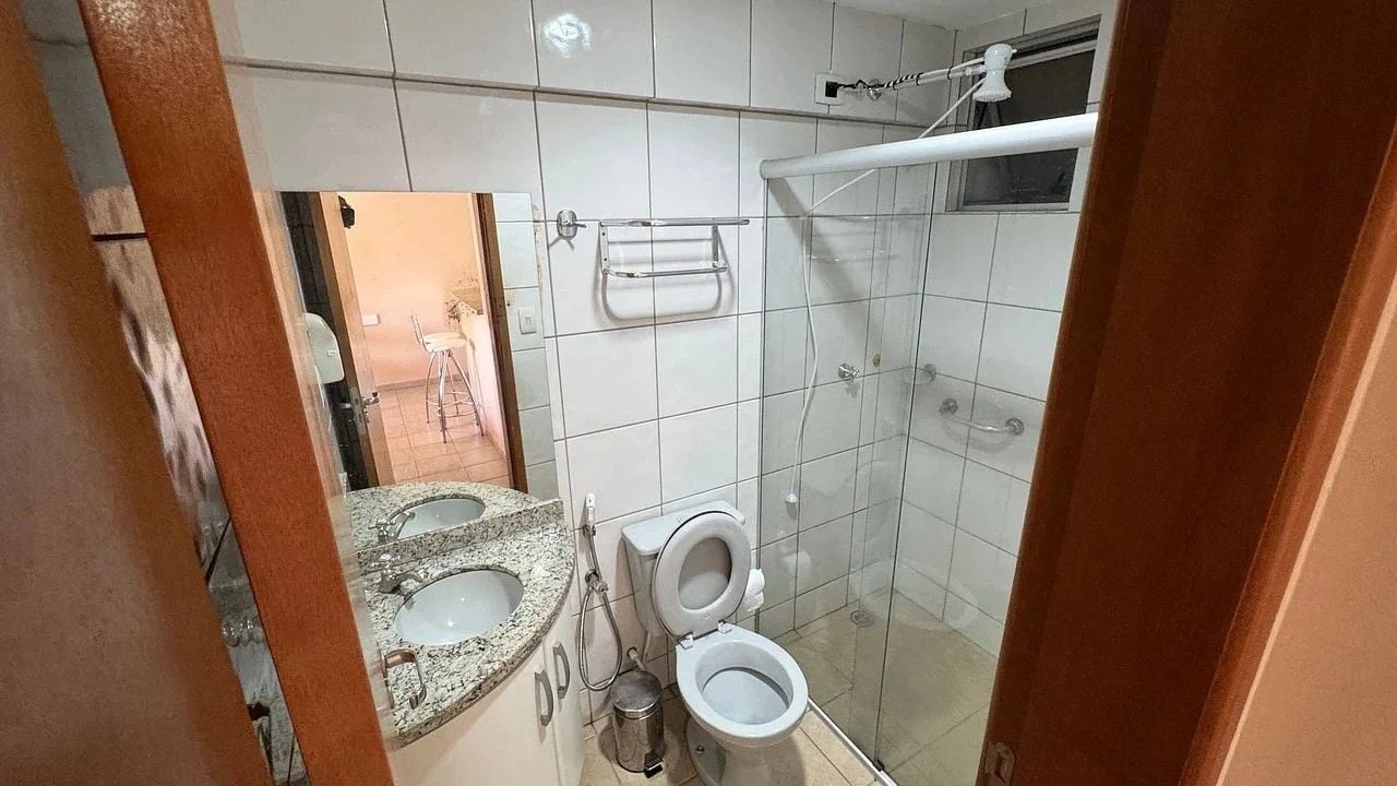 Casa de banho com duas pias, sanita e chuveiro.
