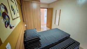 Una habitación con una cama, un armario y una puerta que da a otra estancia.
