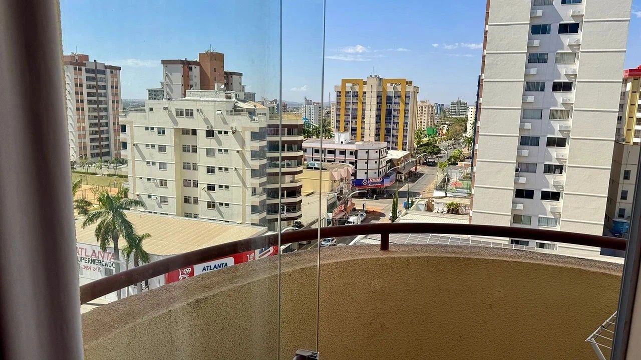 Vista des d'un balcó amb terra sorrenca, edificis al fons i un cel serè.