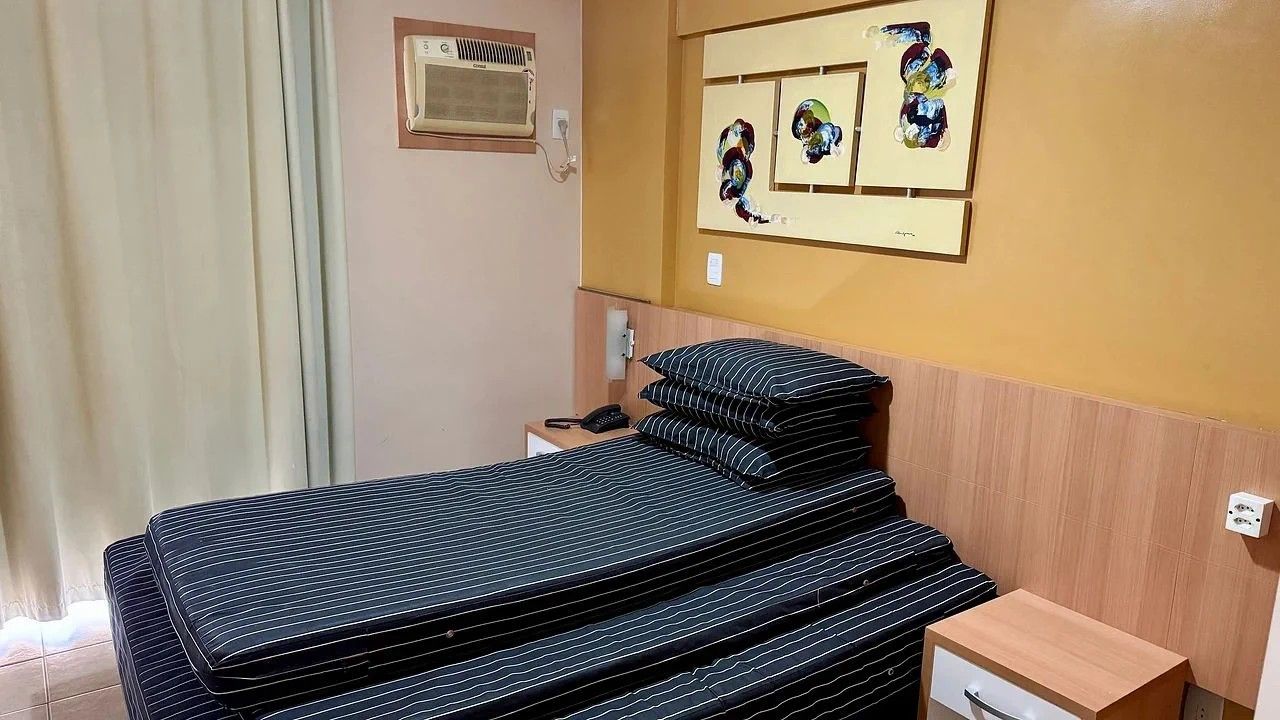 Een hotelkamer met een bed, nachtkastje, spiegel en kunst aan de muur.