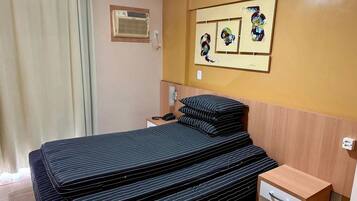 Een hotelkamer met een bed, nachtkastje, spiegel en kunst aan de muur.