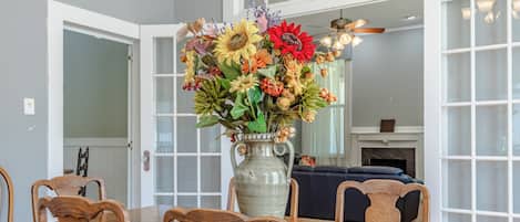 A dining area with a wooden table, chairs, and a vase of flowers.