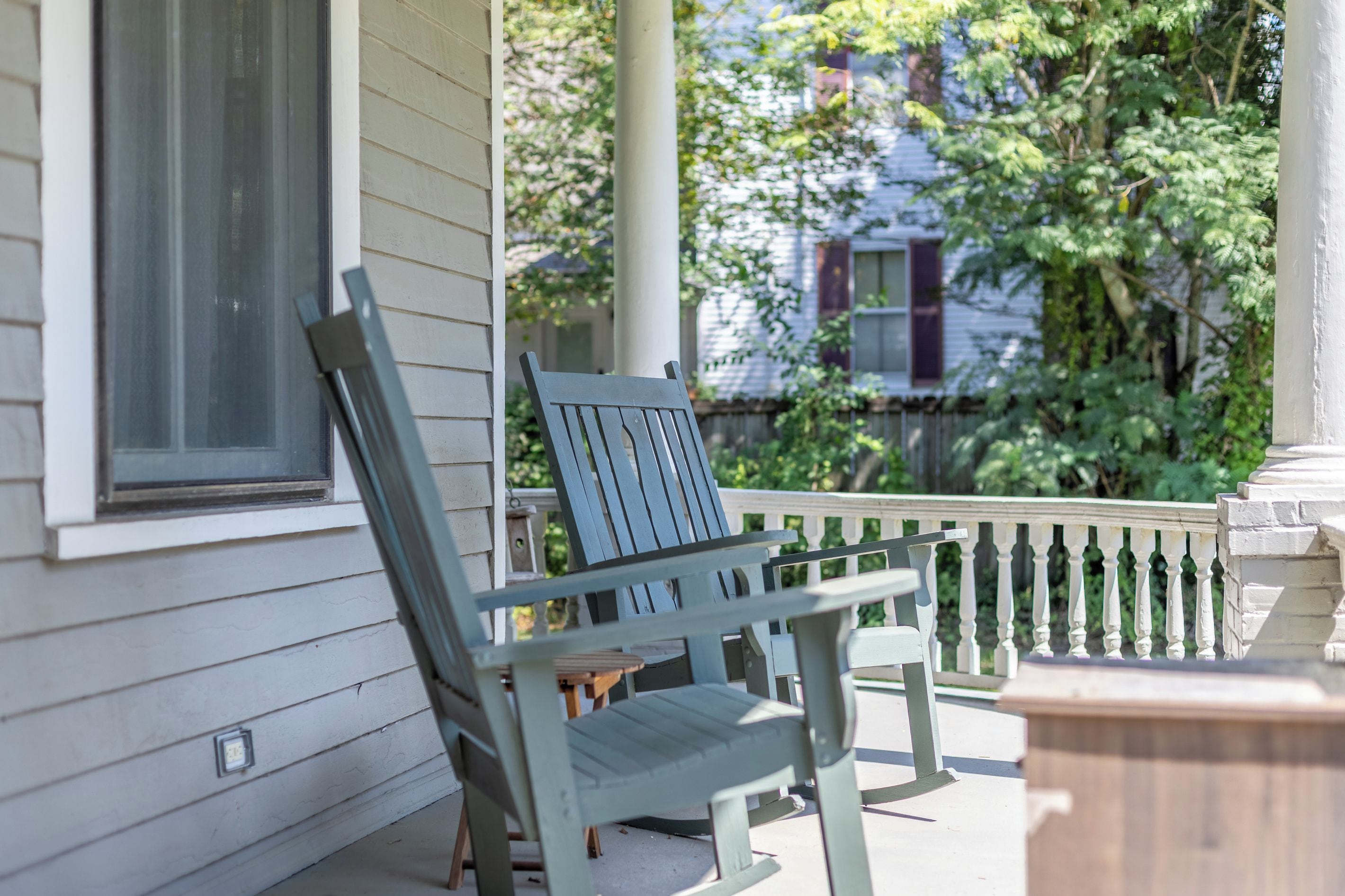 A porch with a wooden bench and a white railing.