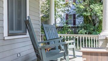 A porch with a wooden bench and a white railing.