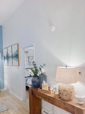 A room with a wooden console table, a lamp, a vase with flowers, and a framed picture on the wall. - Newly Renovated Condo at Ski Wintergreen Resort (Wintergreen Resort)