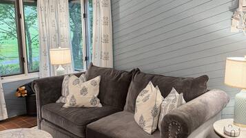 A living room with a grey sofa, patterned cushions, a round coffee table, and a blue patterned rug.