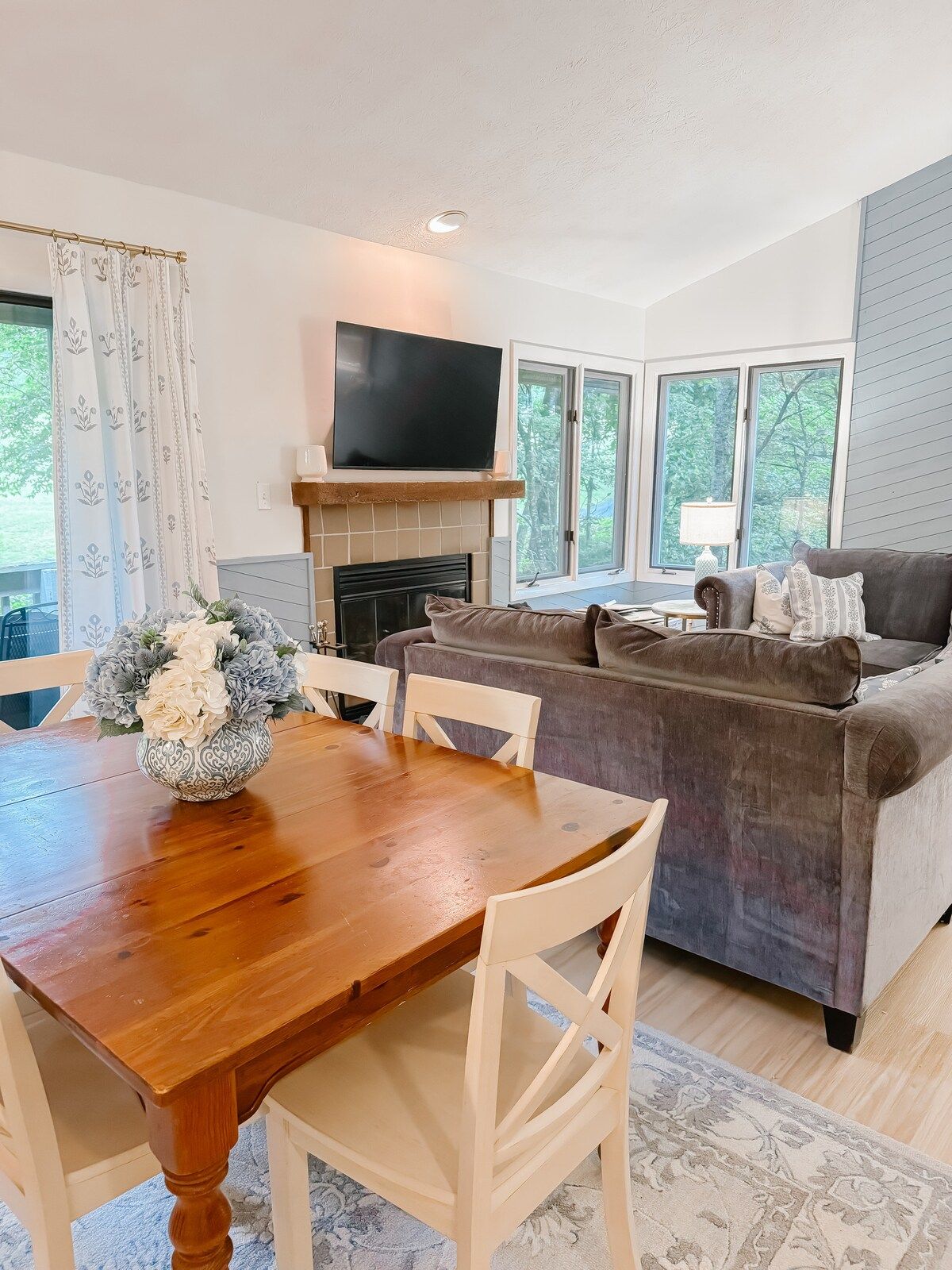 A living room with a fireplace, a flat-screen TV, a sofa, and a dining table with chairs.