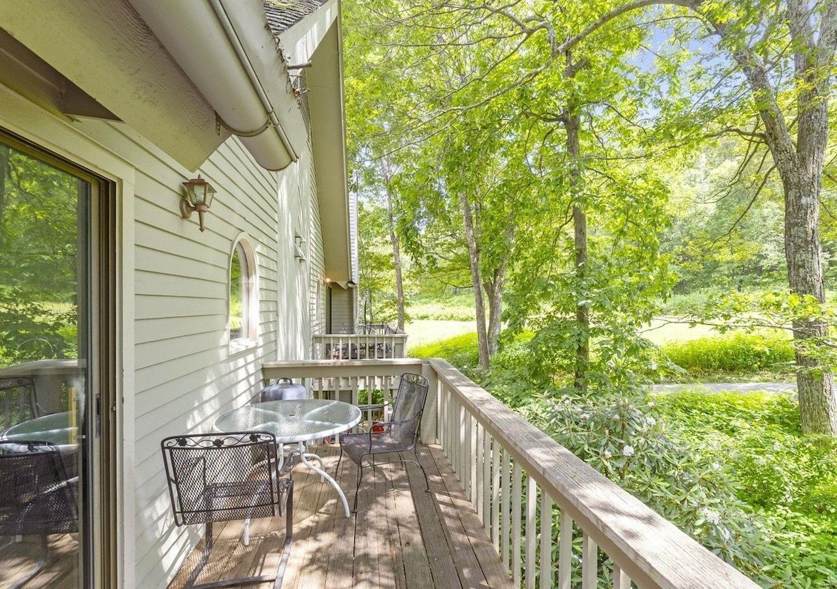 A wooden deck with a table and chairs, overlooking a lush green landscape.