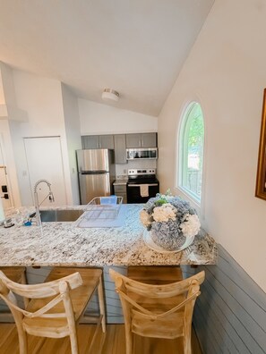 A modern kitchen with stainless steel appliances, a marble countertop, and a dining area with wooden chairs. - Newly Renovated Condo at Ski Wintergreen Resort (Wintergreen Resort)