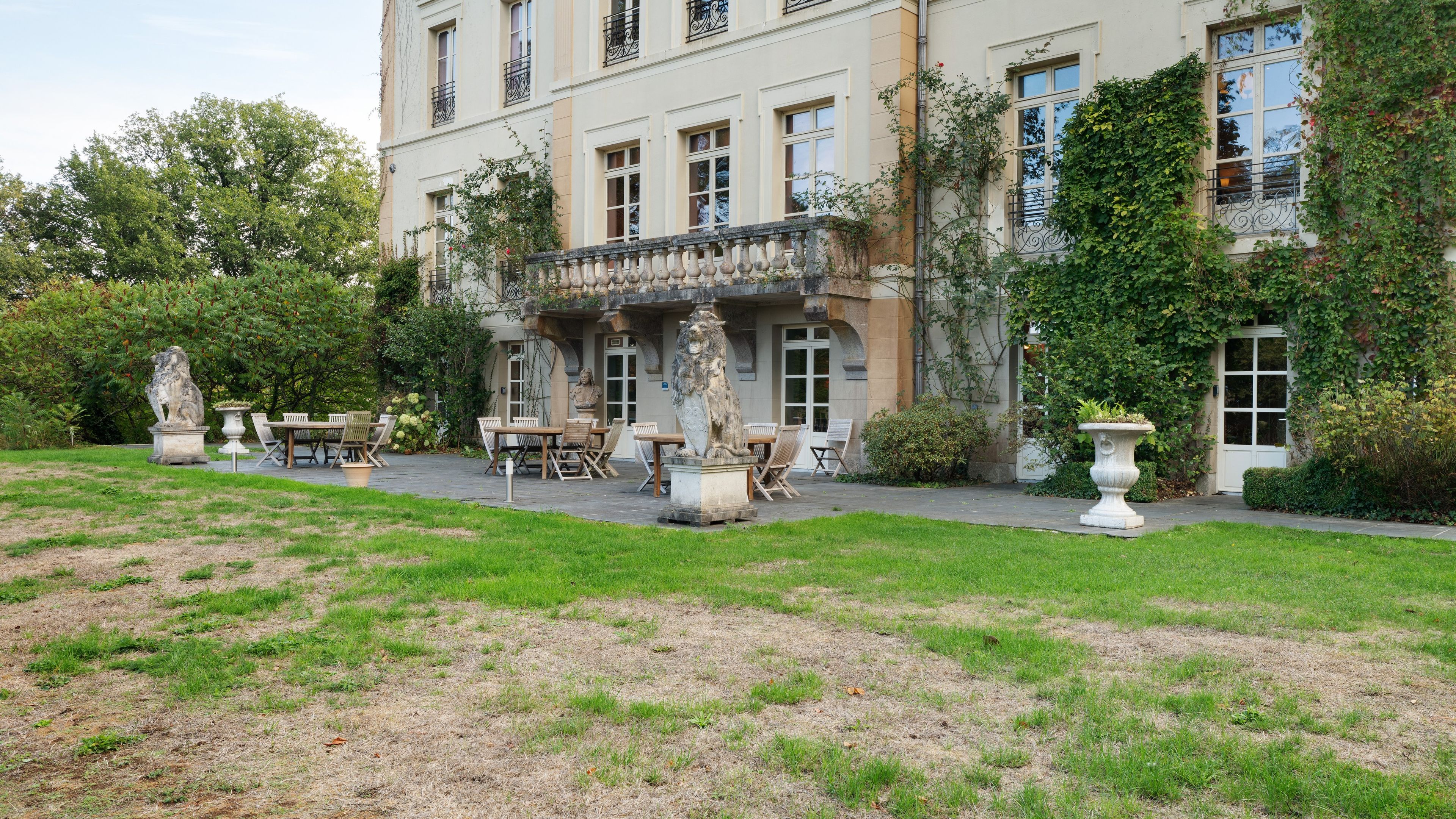 Un bâtiment doté d’un patio avec jardin, d’un espace extérieur aménagé pour s’asseoir et d’une statue.