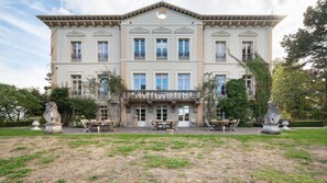 Un edifici gran i imponent amb una façana simètrica, moltes finestres i una entrada central amb un balcó decoratiu.