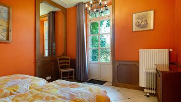 Quarto com duas camas, janela com cortinas, radiador e um quadro na parede.