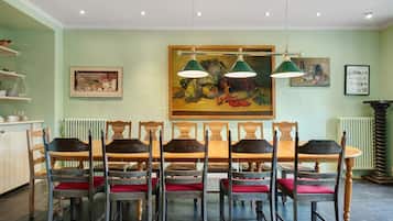 Un coin repas avec une longue table en bois et des chaises, un tableau accroché au mur et un radiateur.