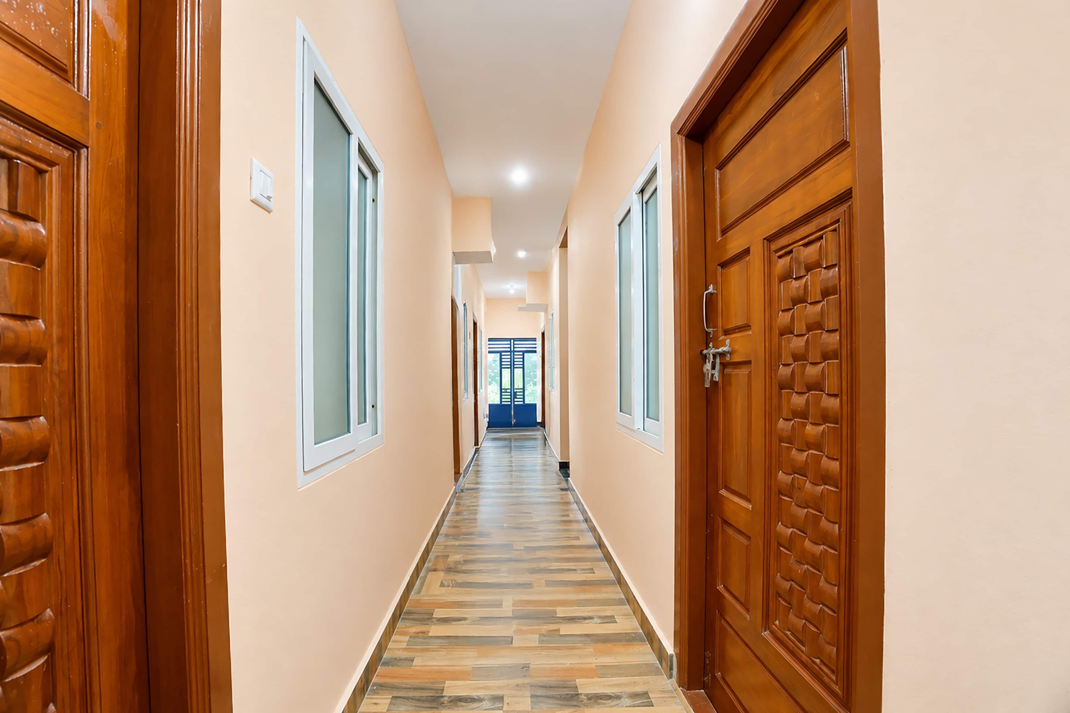 A hallway with wooden doors and windows, leading to a blue door at the end.