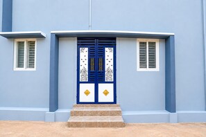 A building with a blue door, white window frames, and a set of stairs leading to the entrance. - Hotel O Red Hill Chennai (Chennai)