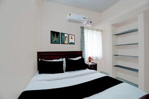 A bedroom with a bed, a nightstand, a wall-mounted air conditioner, and a window with curtains.