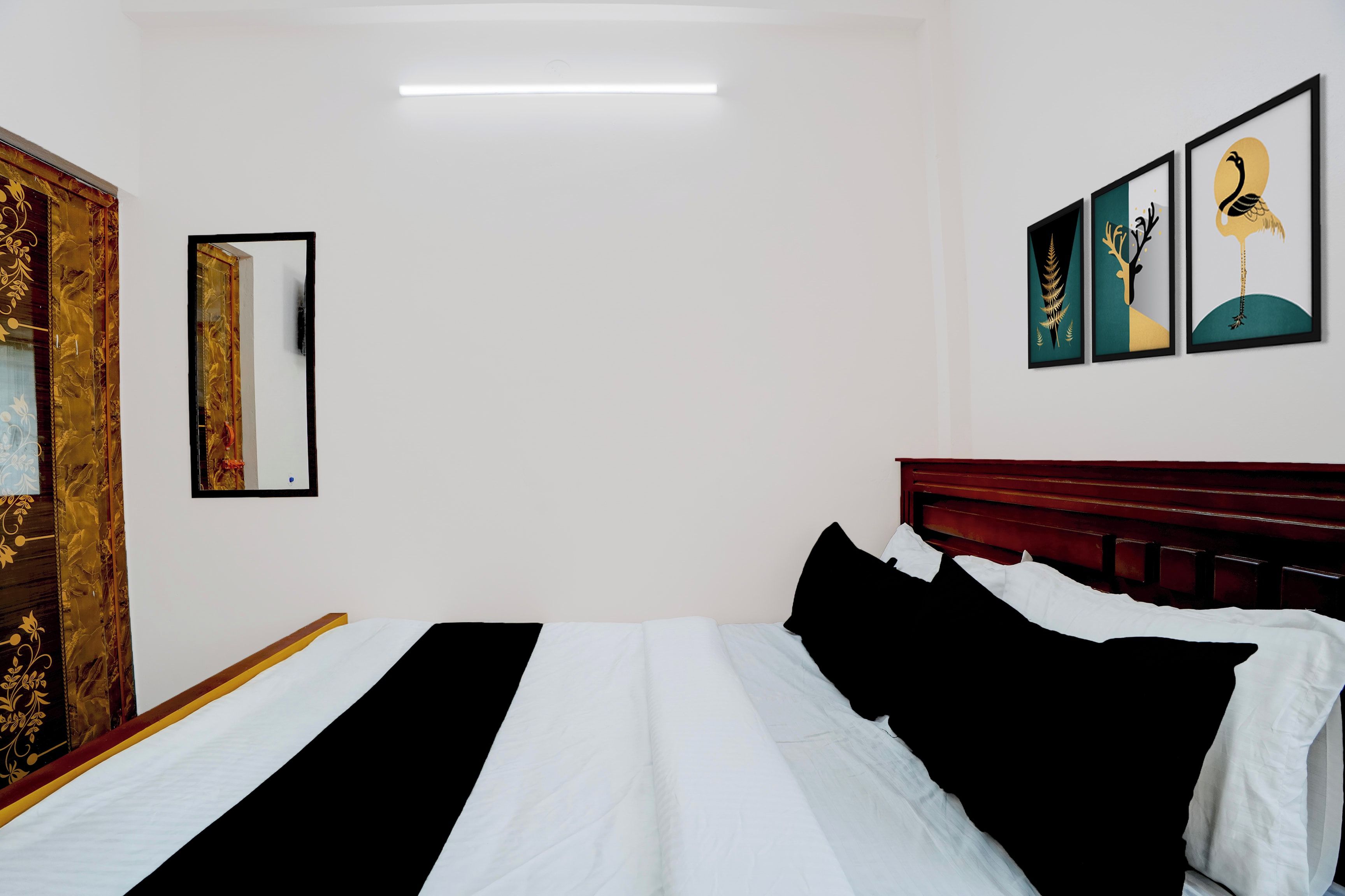 Une chambre d’hôtel avec un lit, un miroir et trois œuvres d’art encadrées accrochées au mur.