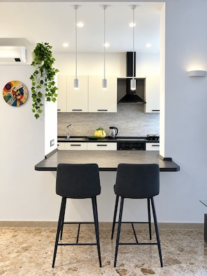 Eine moderne Küche mit einer zentralen Kochinsel, Pendelleuchten und einem Blumentopf.