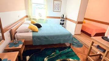 Habitación de hotel pequeña con cama, mesitas de noche, escritorio y una silla.