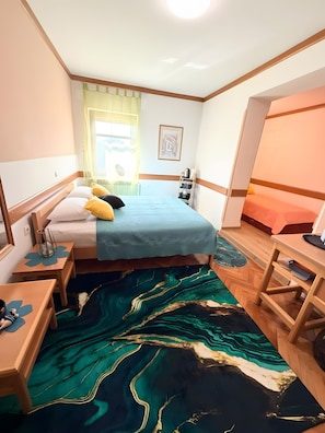 A compact hotel room with a bed, bedside tables, a desk, and a chair.