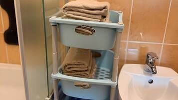 A bathroom with a glass shower enclosure, a white sink, and a blue towel rack with folded towels.