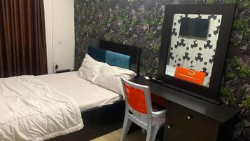 Un dormitorio con cama, escritorio, silla y televisor montado en la pared.