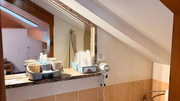 A bathroom with a sink, towel rack, and a hairdryer on the countertop.