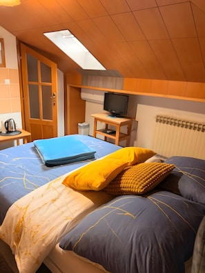 A bedroom with a bed, a desk with a television, a window, and a radiator. - Apartment 'Baroko Rooms  Apartments' with Wi-Fi and air conditioning (Varaždin)