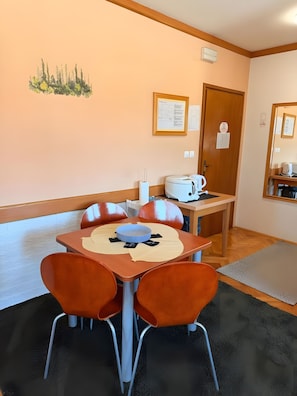 Un comedor con una mesa, sillas, un hervidor y un menú colgado en la pared.