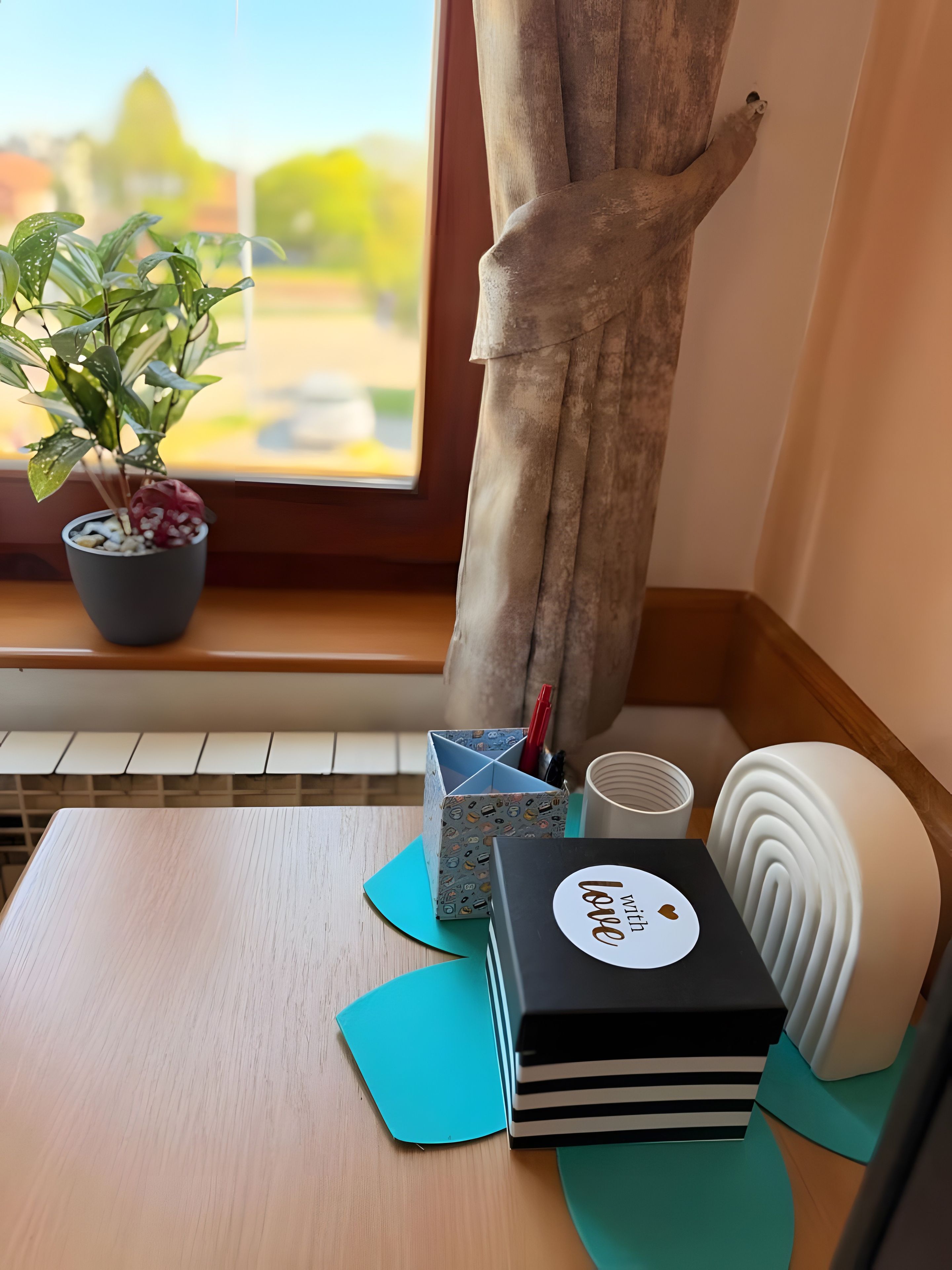 A wooden table with a potted plant, a decorative tree trunk, a storage box, and a black box with a white label.