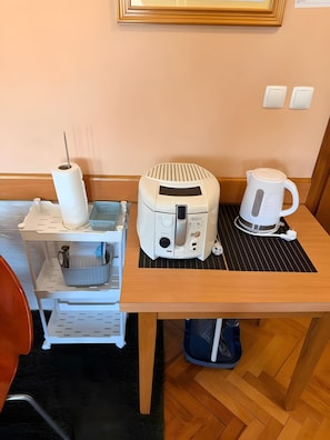 Una kitchenette con tostadora, hervidor de agua y un pequeño estante blanco con un rollo de toallas de papel.