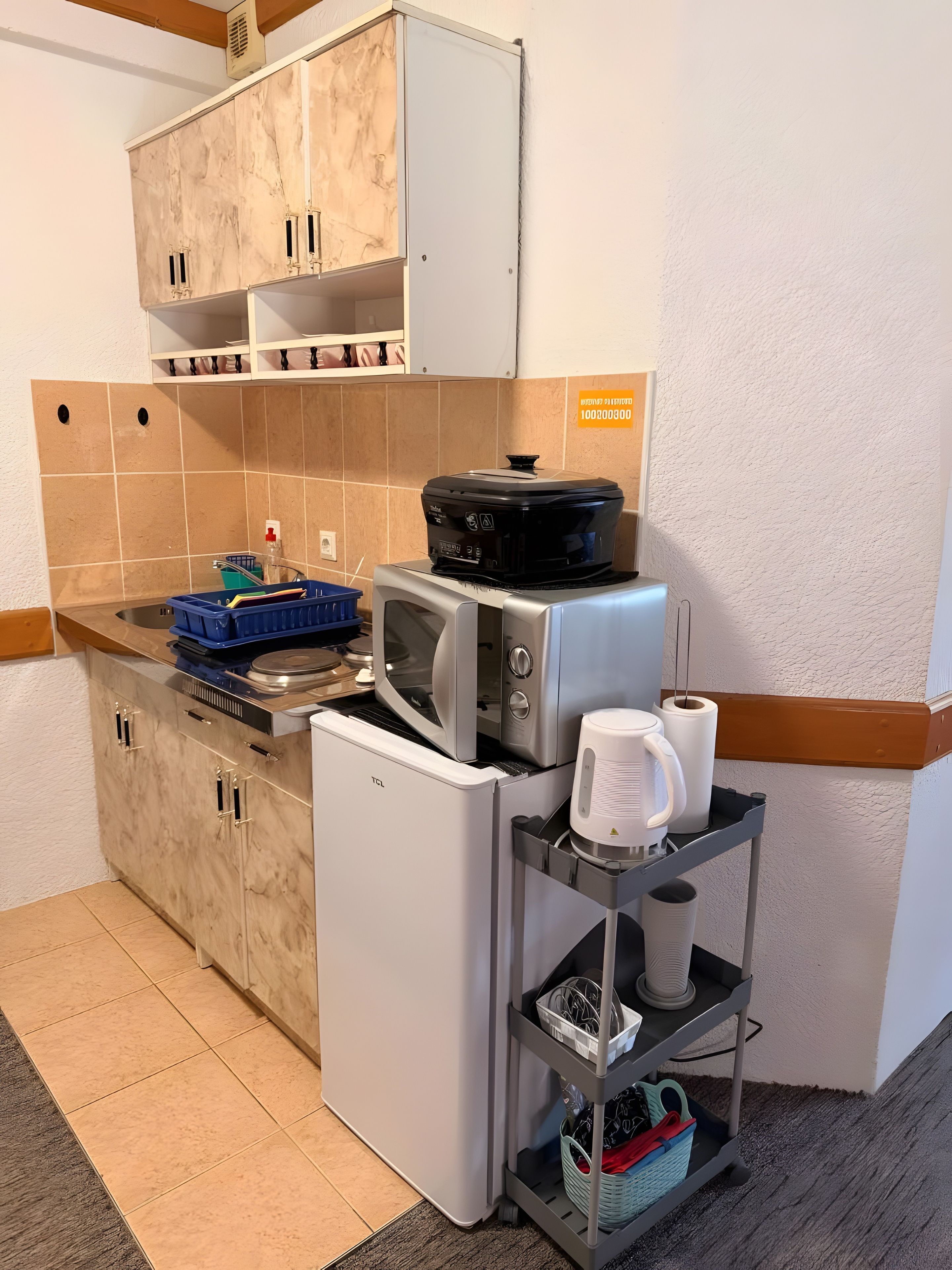 Ett kompakt kök med mikrovågsugn, brödrost och ett litet kylskåp.