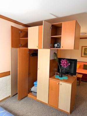 A compact room with a wardrobe, a desk, and a bed.