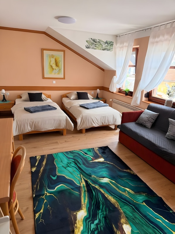 Ein Hotelzimmer mit zwei Betten, einem Sofa, einem großen abstrakten Teppich und einem Gemälde an der Wand.