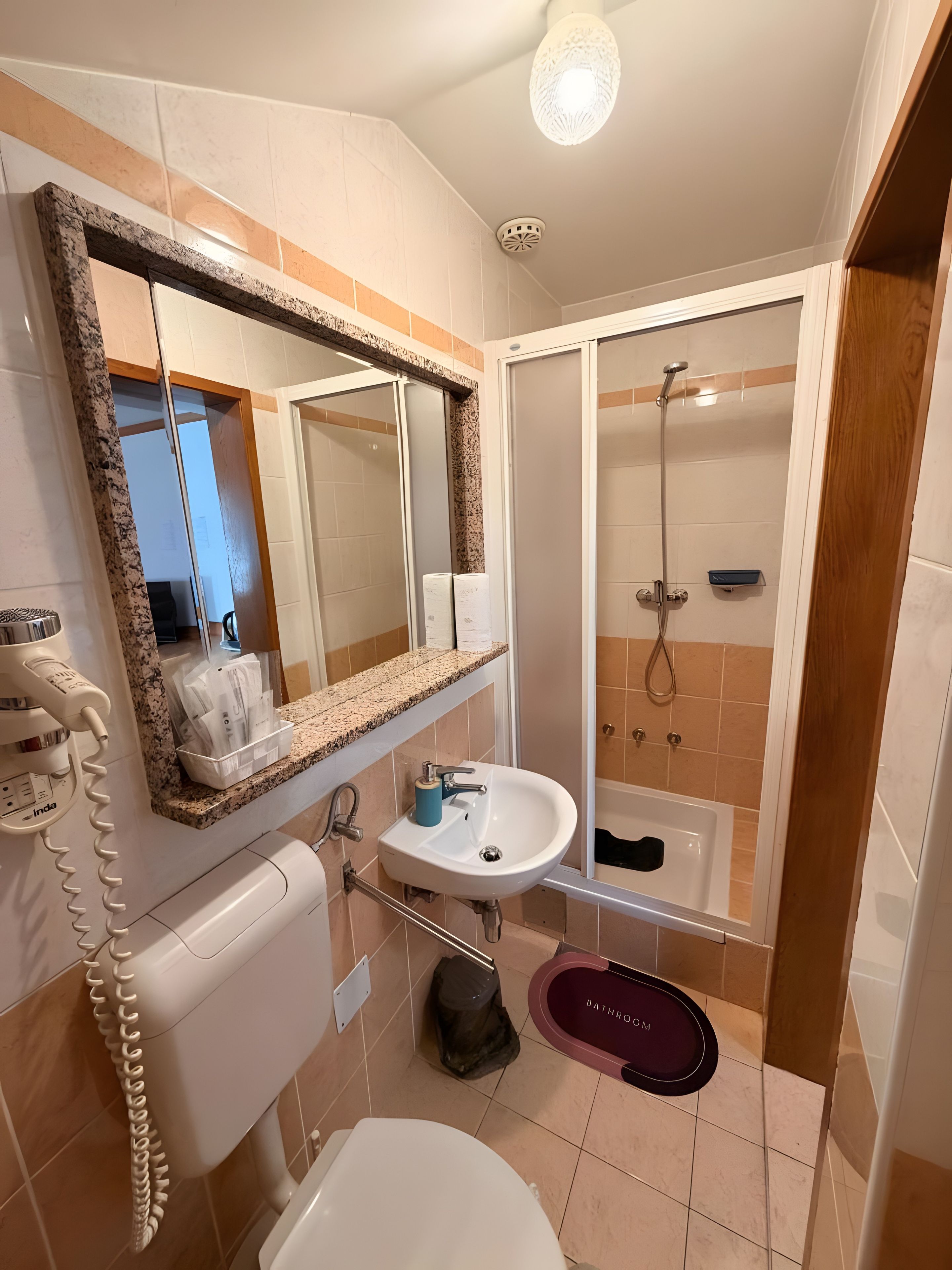 Een badkamer met toilet, wastafel, douche en een spiegel.