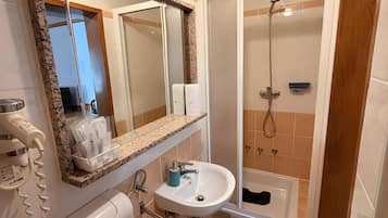 Een badkamer met toilet, wastafel, douche en een spiegel.